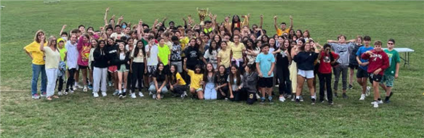 Large Group of students on a field holding a trophy.